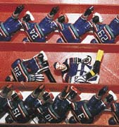 Ručně malovaní hokejisté čekají na střídačce na svůj okamžik