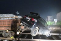 Řidič vjel na rozkopaný železniční přejezd: S autem skončil na odstaveném vagonu